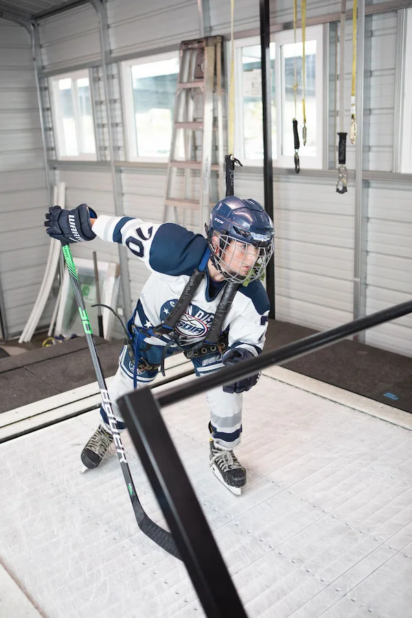A coach works beside a hockey player during a Power Stride treadmill session